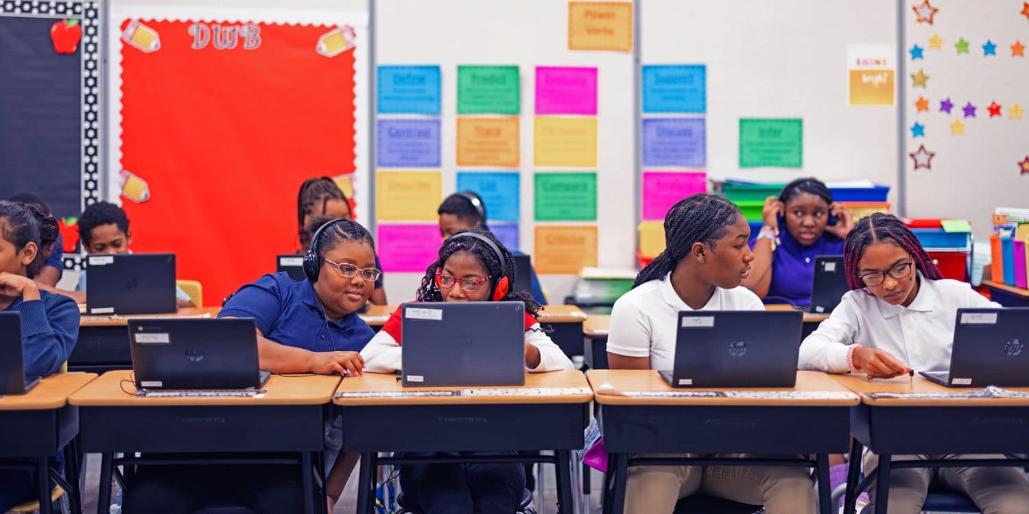 Students working on laptops at their classroom desks.