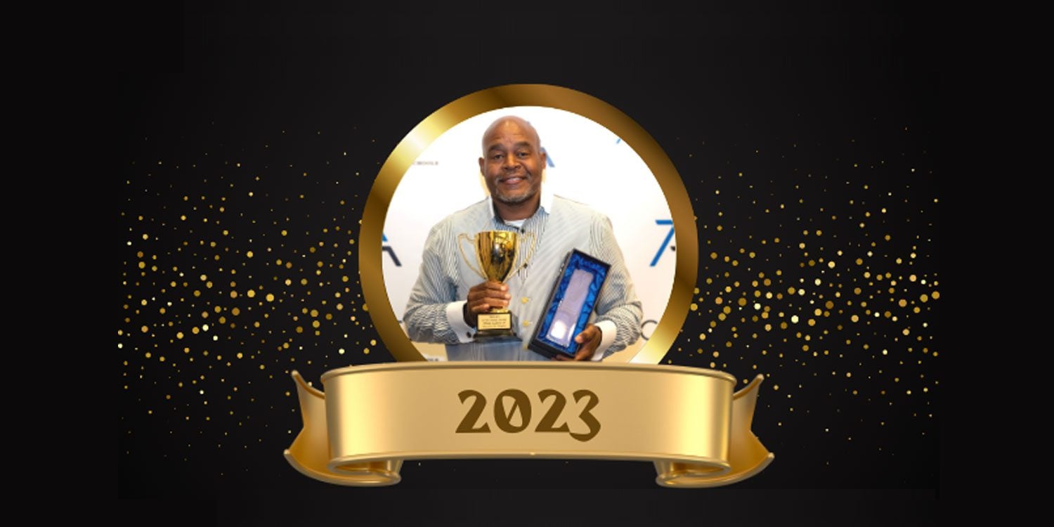 Adult holding a golden trophy and a blue award plaque.